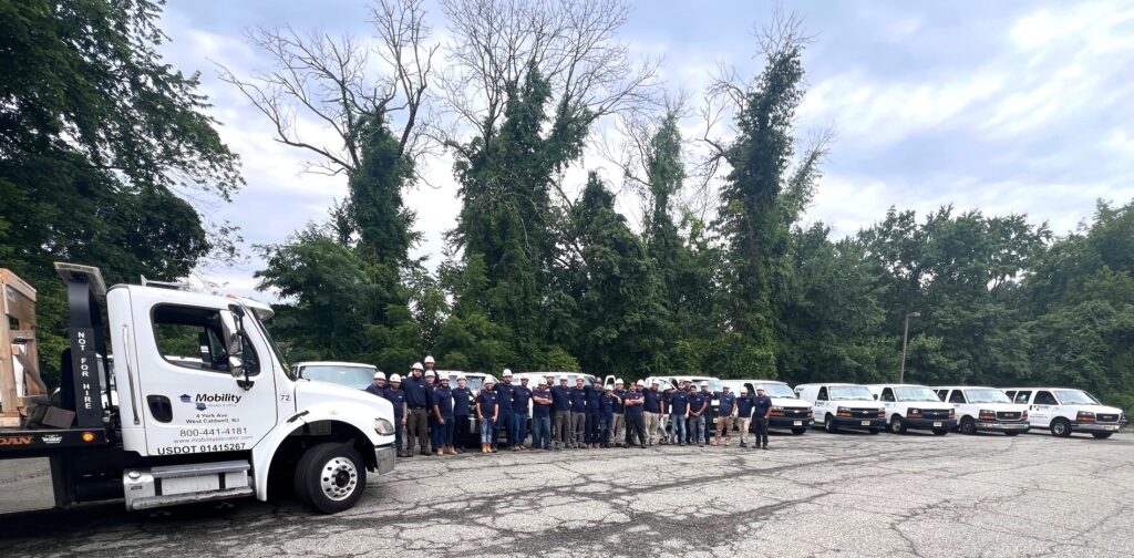 The Mobility Elevator staff outside in a parking lot with their trucks nearby